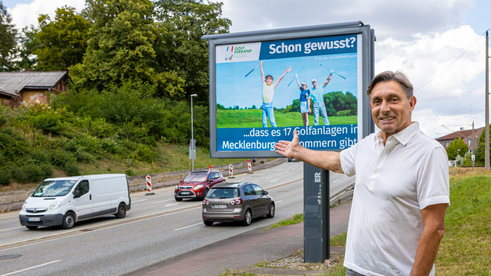 Rüdiger Born, der Präsident des Landesgolfverbandes MV vor einem der Großplakate in Schwerin.